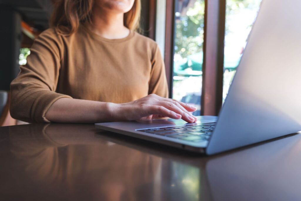 Een close-up van een vrouw werkend achter haar laptop.